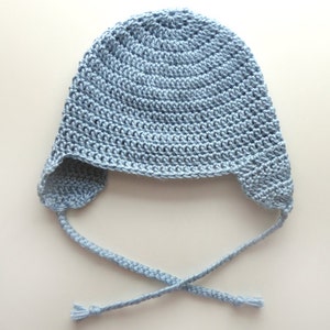 May include: A light blue crocheted baby hat with ear flaps and a tie string.