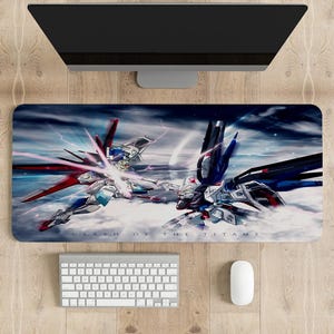May include: A rectangular mousepad featuring a dynamic illustration of two mecha robots in a battle scene with a cloudy sky background. The text "CLASH OF THE TITANS" is at the bottom. A keyboard, mouse, and monitor are also visible.