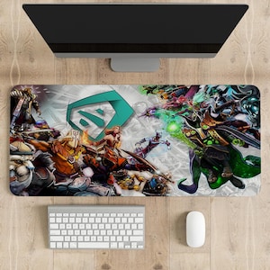 May include: A rectangular gaming mousepad featuring a colorful illustration of characters from a video game. The design includes a teal logo and various action poses of the characters. A computer monitor, keyboard, and mouse are visible.