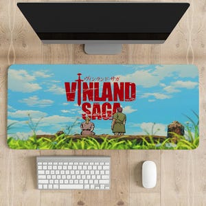 Puede incluir: Alfombrilla de ratón rectangular con el título del anime "Vinland Saga" en letras rojas sobre un fondo de cielo azul. Dos figuras están representadas en una colina cubierta de hierba. También se ven un teclado, un ratón y un monitor.