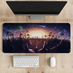 Pode incluir: Tapete de mesa retangular com uma paisagem de fantasia com um pôr do sol, árvores e elementos celestes. Um monitor de computador, teclado e mouse estão acima e abaixo do tapete em uma superfície de madeira.