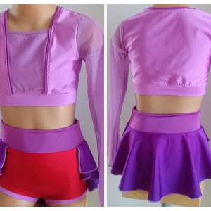 Op de afbeelding: Een tweedelig danskostuum in paarse en rode tinten. De top is een cropped ontwerp met lange mouwen en een vierkante halslijn. De shorts zijn rood met paarse accenten en de rok is paars. Het kostuum is ontworpen voor dans of optredens.