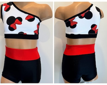 May include: A white and black one-shoulder crop top with red polka dot bows and a black and red high-waisted shorts set.