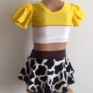 May include: A two-piece costume for a child, featuring a yellow and white top with puffed sleeves and a black and white cow print skirt with a brown waistband.