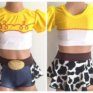 May include: A yellow and white crop top with a red and white trim and a cow print skirt with a brown belt. The top has a design of a lasso and stars.