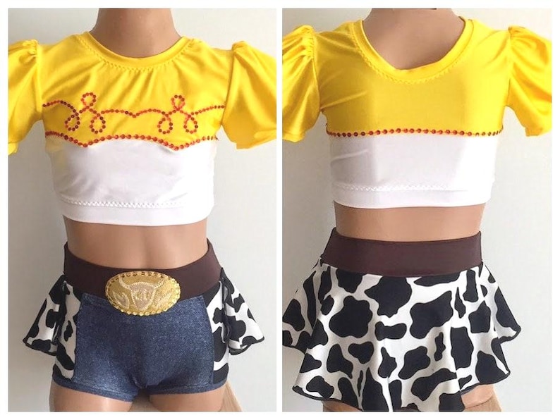 May include: A yellow and white crop top with a red and white trim and a cow print skirt with a brown belt. The top has a design of a lasso and stars.