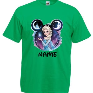 May include: A green t-shirt featuring a graphic of a princess holding a star, with a castle and moon design. The word "NAME" is printed in black below the princess image. The princess is wearing a blue dress.