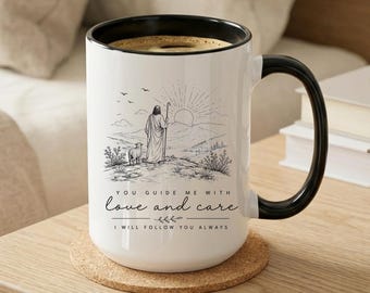 May include: A white ceramic mug with a black handle and rim, featuring a black line art illustration of a figure with a staff and a sheep in a landscape. The text reads: YOU GUIDE ME WITH love and care I WILL FOLLOW YOU ALWAYS.