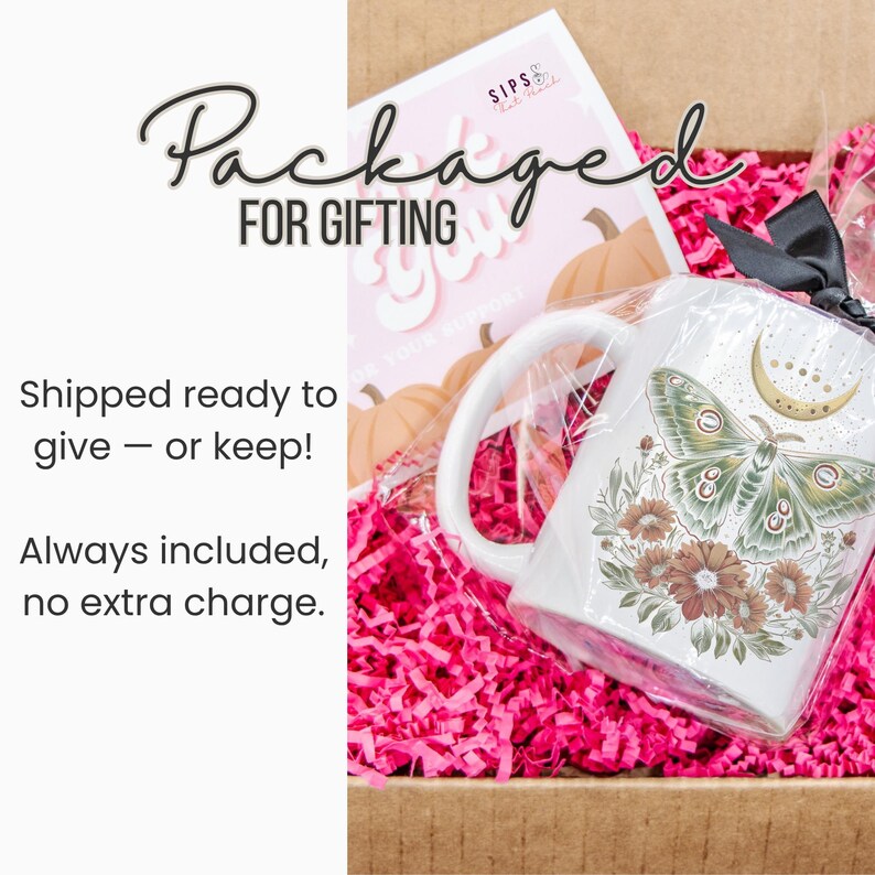 May include: A white mug with a moth and floral design, packaged in a gift box with pink filler. The mug has a crescent moon and floral design. The box includes a card that says "Packaged for Gifting".