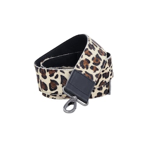 May include: A brown and white leopard print camera strap with a black leather adjustable strap and a silver metal hook.