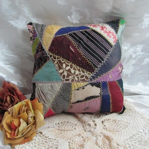 May include: A patchwork pillow with a variety of colors and patterns, including burgundy, green, blue, and white. The pillow is made of fabric scraps sewn together in a random pattern.