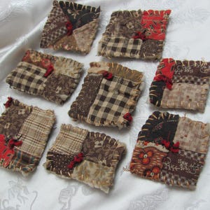 May include: A collection of nine handmade fabric coasters. Each coaster is square, pieced together from various patterned fabrics in shades of brown, beige, and red. The edges are stitched with a contrasting thread and adorned with small red accents.