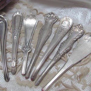 May include: Seven antique silver serving spoons with ornate handles. The spoons have a variety of designs, including floral, geometric, and engraved patterns.