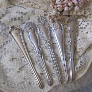 May include: Five silver-plated serving spoons with ornate handles. The spoons have a vintage look and are perfect for a formal dinner setting.