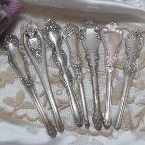 May include: Set of eight silver-plated serving spoons with ornate handles. The spoons have a vintage look and are perfect for adding a touch of elegance to any table setting.