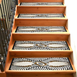 May include: A set of five black and white patterned stair treads with gold accents. The treads are designed to prevent slipping on stairs.