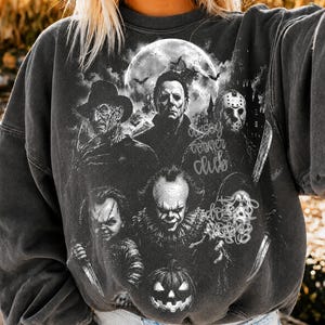 May include: A charcoal gray crewneck sweatshirt featuring a black and white graphic print of six iconic horror movie characters arranged around a large full moon, with the text "spooky corner club" and "do not disturb" printed in a script font.