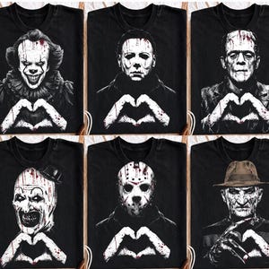 May include: A collection of six black t-shirts, each featuring a high-contrast white graphic of a different horror movie character. Every character is depicted making a heart shape with their hands, with blood splatters visible on the prints.