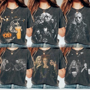 May include: A collection of six charcoal gray t-shirts featuring various horror-themed graphic prints. Designs include a cat with a pumpkin, a group of horror movie villains, a masked figure, two slashers, three witches, and a movie theater scene.