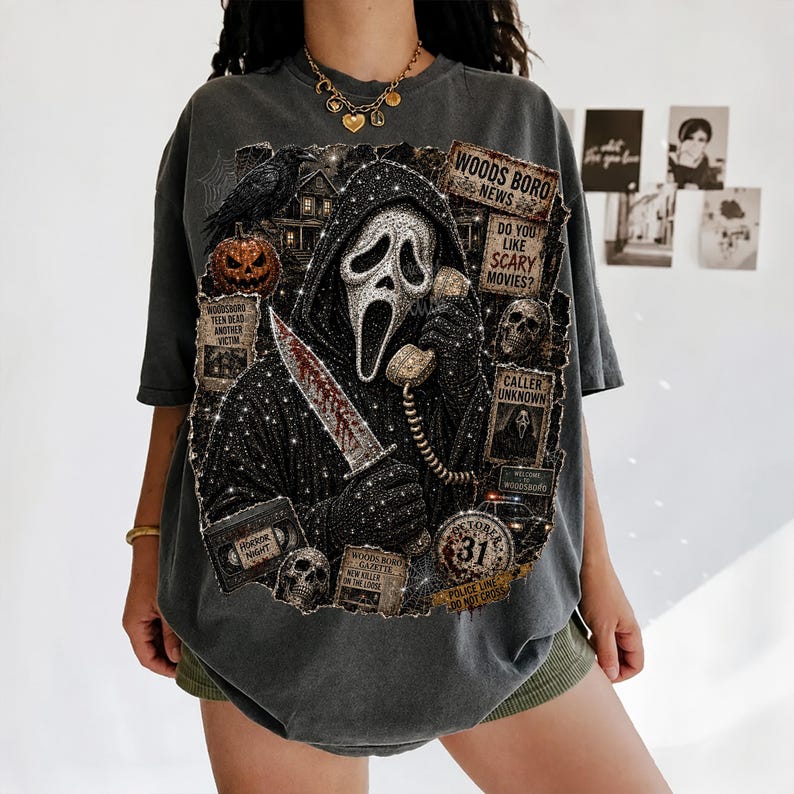 May include: A charcoal gray oversized t-shirt featuring a graphic print of a hooded figure holding a knife and a telephone. The design includes a pumpkin, skulls, a raven, and text boxes reading Woodsboro News, Do You Like Scary Movies, and Caller Unknown.