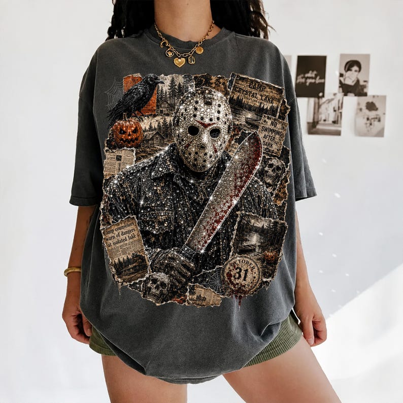 May include: A charcoal gray oversized t-shirt featuring a graphic print of a hockey mask-wearing figure holding a machete. The design includes a raven, a pumpkin, skulls, and text reading Camp Crystal Lake, No Swimming After Dark, and October 31.