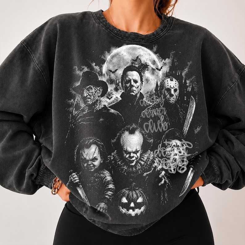 May include: A charcoal grey acid-wash crewneck sweatshirt featuring a large black and white graphic print of five iconic horror movie characters, a full moon, and a pumpkin. The text "spooky corner club" is printed in a cursive script overlay.
