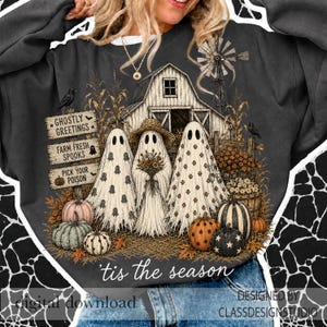 Puede incluir: Una sudadera gris oscuro con un gr&aacute;fico de tres fantasmas frente a un granero. Los fantasmas est&aacute;n rodeados de calabazas, flores y letreros que dicen Ghostly Greetings, Farm Fresh Spooks y Pick Your Poison. El texto 'tis the season' est&aacute; debajo.