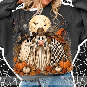 Puede incluir: Una sudadera gris oscuro con un gr&aacute;fico de tres fantasmas con sombreros. El fantasma de la izquierda lleva un sombrero negro con estrellas, el del centro un sombrero de vaquero y hace una pompa, y el de la derecha un sombrero naranja a cuadros. Calabazas, murci&eacute;lagos y un granero al fondo.