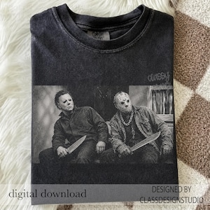 Może przedstawiać: Ciemnoszary t-shirt z okrągłym dekoltem i czarno-białym nadrukiem przedstawiającym dwie postacie z horror&oacute;w. Jedna postać ma na sobie maskę i trzyma n&oacute;ż, a druga maskę hokejową i maczetę. Koszulka posiada efekt sprania w stylu vintage.