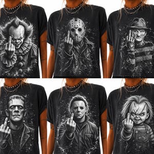 May include: A collection of six black t-shirts, each featuring a white graphic illustration of a different horror movie character. Every character is depicted making a middle finger gesture. The designs include Pennywise, Jason Voorhees, Freddy Krueger, Frankenstein's monster, Michael Myers, and Chucky, all set against a dark, splattered background.