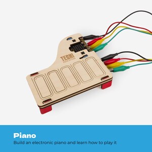 Pode incluir: Um kit de piano eletr&oacute;nico de madeira clara com o texto TECHI EDUCATION impresso na superf&iacute;cie. O dispositivo possui cinco teclas retangulares sens&iacute;veis ao toque e est&aacute; ligado a um controlador micro:bit com cabos de pin&ccedil;as de crocodilo vermelhos, amarelos e verdes.