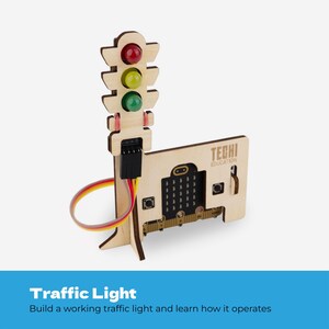 Pode incluir: Um modelo de sem&aacute;foro de madeira com luzes circulares transl&uacute;cidas nas cores vermelha, amarela e verde. A estrutura inclui uma base com o texto TECHI EDUCATION e uma placa de microcontrolador com bot&otilde;es, conectada por um cabo plano colorido.