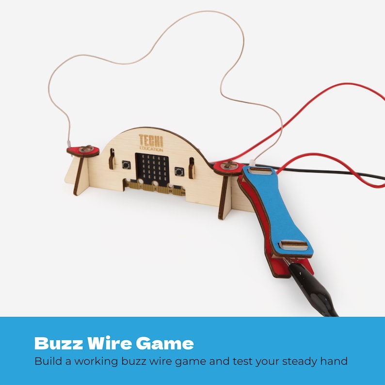 Pode incluir: Um kit de jogo de fio el&eacute;trico de madeira com uma placa de microcontrolador central com o texto TECHI EDUCATION, um la&ccedil;o de fio de metal curvo e uma al&ccedil;a azul conectada por fios el&eacute;tricos vermelhos e pretos com clipes jacar&eacute; para montagem.
