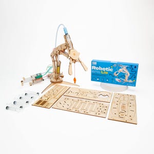 Könnte beinhalten: Ein Roboterarm-Bausatz aus Holz mit einer blauen Box, auf der "Robotic Lio" steht und einem blauen Hintergrund. Der Bausatz enthält einen Holzarm, eine Spritze und eine Vielzahl weiterer Teile.