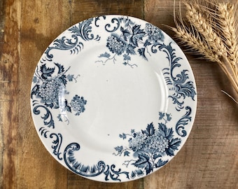 May include: A white ceramic plate with a blue and white floral design. The plate features a delicate floral pattern with intricate details.