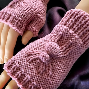 May include: A pair of pink knitted fingerless gloves with a pom-pom detail on each cuff.