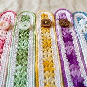 May include: Five crocheted wristlets with different coloured patterns and buttons. The wristlets are pink, green, yellow, purple, and blue.