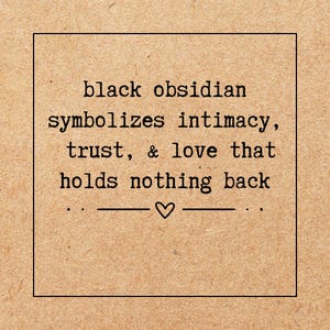 May include: A square, tan-colored card with black text that reads "black obsidian symbolizes intimacy, trust, & love that holds nothing back." A small heart symbol is centered below the text.