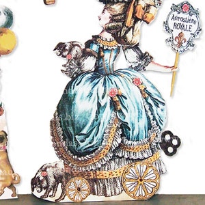 May include: A paper cutout of a woman in a teal dress with a large skirt, holding a sign that reads "Aerostiere ROYALE". The woman is accompanied by a small dog and is mounted on wheels. The dress has gold trim and lace.