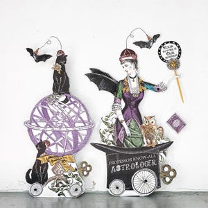 May include: Paper cutouts of a fortune teller and a cat on a globe. The fortune teller wears a purple dress and holds a sign that says "Your Future Is Our Business." A black cat sits atop a purple globe.