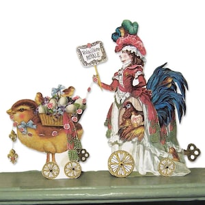May include: A whimsical paper cutout featuring a bird pulling a basket of eggs and flowers, and a woman in a rooster costume. The woman holds a sign that reads "Volaille Royale". The figures are on wheels and decorated with gold accents.