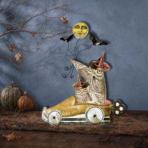 May include: A whimsical Halloween decoration featuring two owls in witch hats riding in a vintage car. A yellow moon with a face and two bats are attached above the car. The car is gold with black and white wheels.
