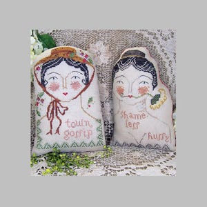 May include: Two decorative fabric dolls with embroidered faces and text. One doll wears a hat and says "town gossip." The other doll has a black cap and says "shame less hurry."