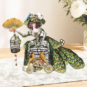 Peut inclure: D&eacute;coupage en papier d'une femme en robe verte avec des d&eacute;tails de plumes de paon. Elle tient un &eacute;ventail et une cage &agrave; oiseaux. Deux oiseaux jaunes sont assis dans une structure en forme de cage avec des roues. Esth&eacute;tique vintage et fantaisiste.