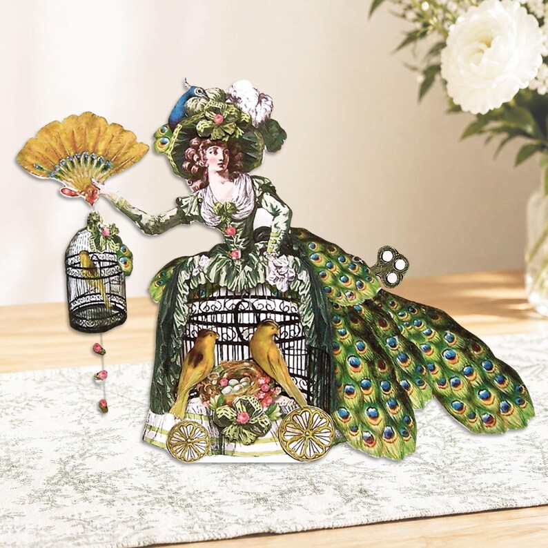 Peut inclure: D&eacute;coupage en papier d'une femme en robe verte avec des d&eacute;tails de plumes de paon. Elle tient un &eacute;ventail et une cage &agrave; oiseaux. Deux oiseaux jaunes sont assis dans une structure en forme de cage avec des roues. Esth&eacute;tique vintage et fantaisiste.