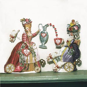 May include: A whimsical paper cutout featuring two women in ornate dresses, each on a wheeled carriage pulled by rabbits. One figure pours hearts from a silver pitcher into a teacup. The image has a vintage aesthetic with the words "The Magic" on a heart.