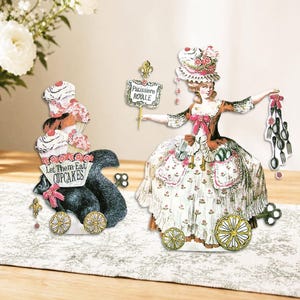 Puede incluir: Recortes de papel caprichosos que representan una ardilla con cupcakes y una mujer con un vestido de época. La ardilla tiene un letrero que dice "Let Them Eat CUPCAKES". La mujer sostiene cucharas y un letrero que dice "Patisserie ROYALE".