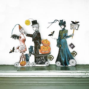 Könnte beinhalten: Eine skurrile Halloween-Illustration mit Papierfiguren und Objekten. Ein Mann mit Zylinder interagiert mit einer Schaufensterpuppe, während eine Frau ein Schild hält. Kürbisse, Fledermäuse und Katzen sind ebenfalls vorhanden. Der Text "Doctor Phrend" ist sichtbar.