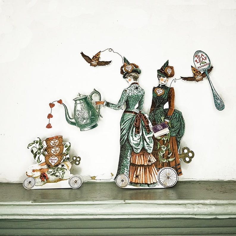 Peut inclure: D&eacute;coupages de papier fantaisistes repr&eacute;sentant des femmes de l'&eacute;poque victorienne, une th&eacute;i&egrave;re, un lapin sur roues et un hibou avec une cuill&egrave;re. Les femmes portent des robes &eacute;labor&eacute;es. La th&eacute;i&egrave;re a un jet en forme de c&oelig;ur. Le hibou tient une cuill&egrave;re avec "Tea Leaf Reading".