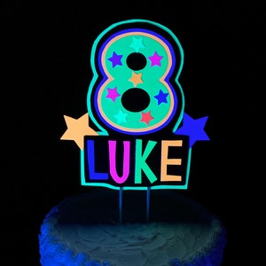 number 8 in neon green with LUKE in neon colors as a glow party birthday personalized cake topper that fluoresces under UV reflective black light